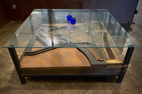 Glass top table with part of piano underneath the glass